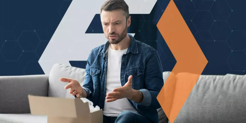 Man sitting on a couch and opening a mid-sized package, looking confused at its condition and contents